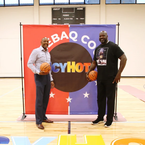 Shaquille O'Neil and Alonzo Mourning standing on the Miami Comebaq Court. Each of them have a basket ball on their right hands.